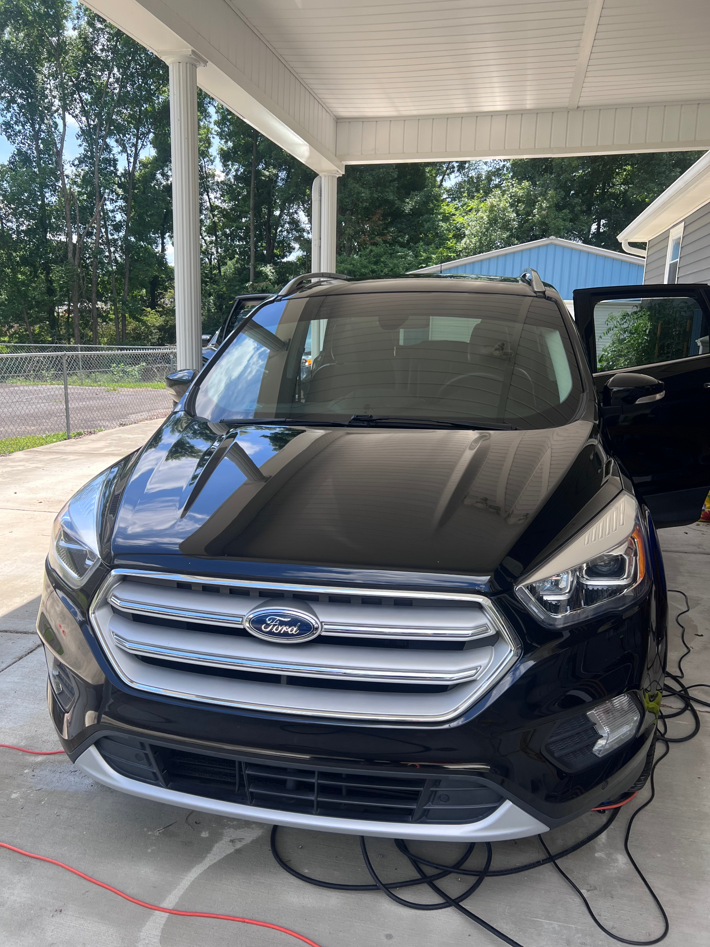 Glossy black Ford Escape parked under a carport after a mobile detail