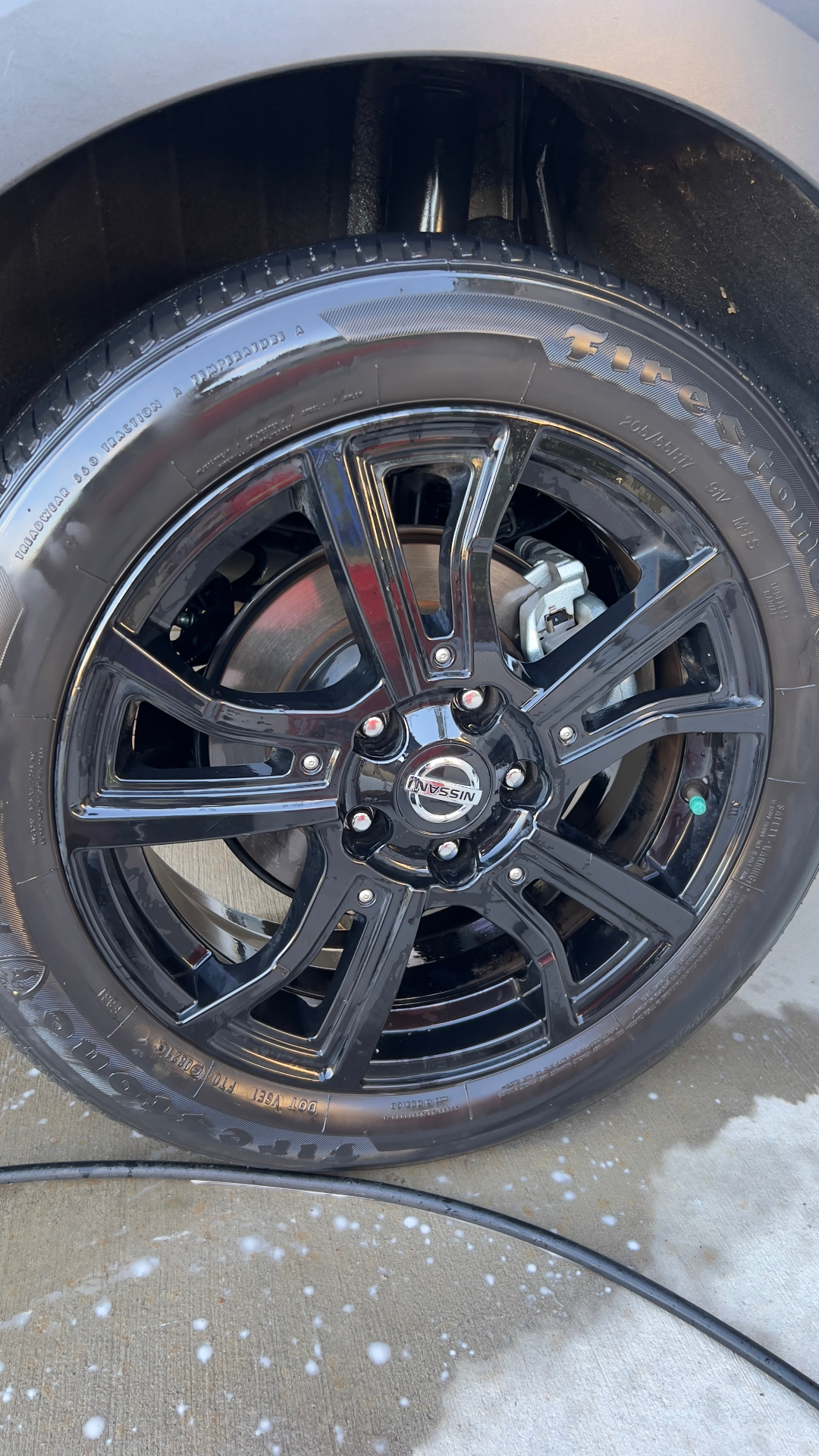 Close-up of a glossy black Nissan wheel after tire shine and wheel detail